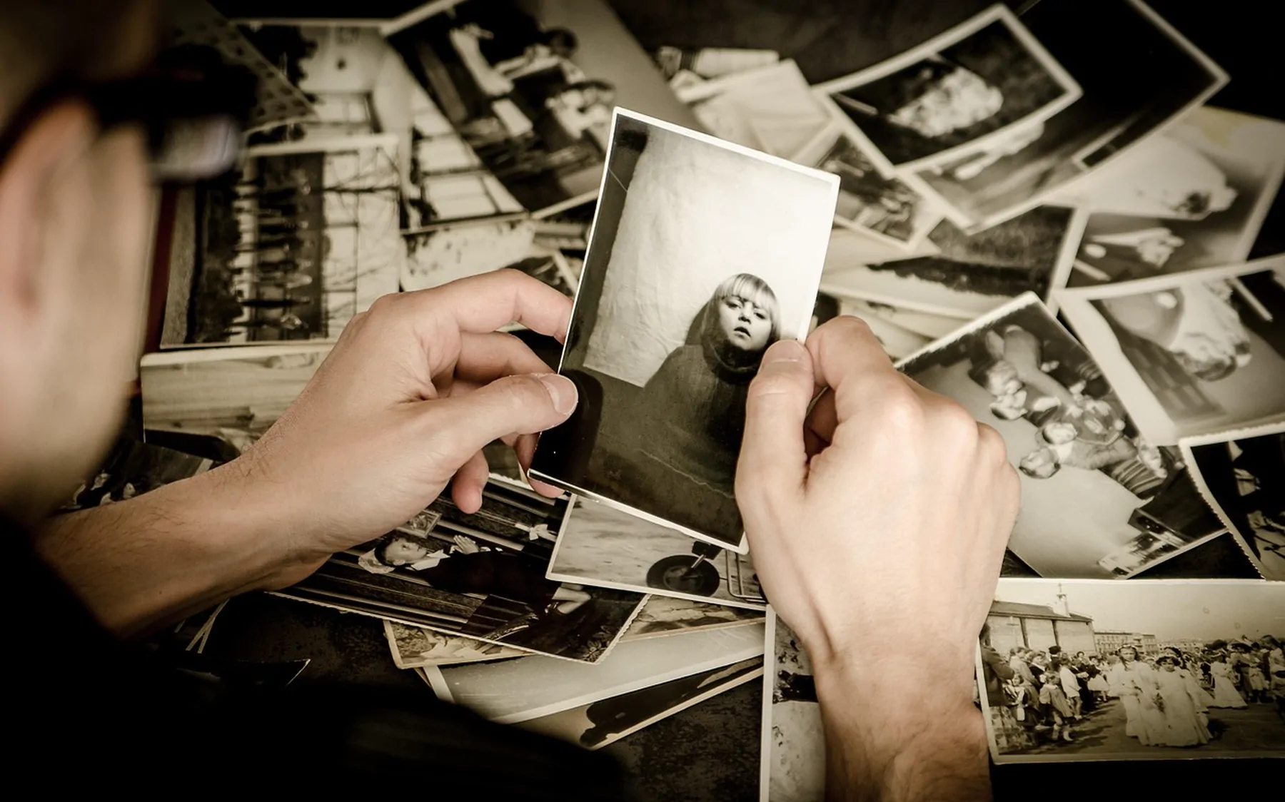 Hands sorting through a spread of old black and white photographs
