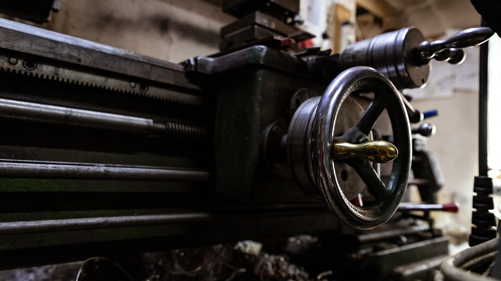 A metalworking lathe in a workshop, lit from the side